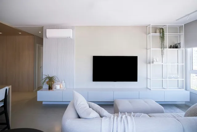 A bright, sparsely furnished apartment living room with a low sofa, pale walls and an open floor area