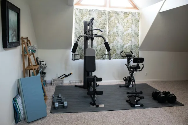 A home gym set up on a soft carpeted floor with a rubber mat laid under the machine